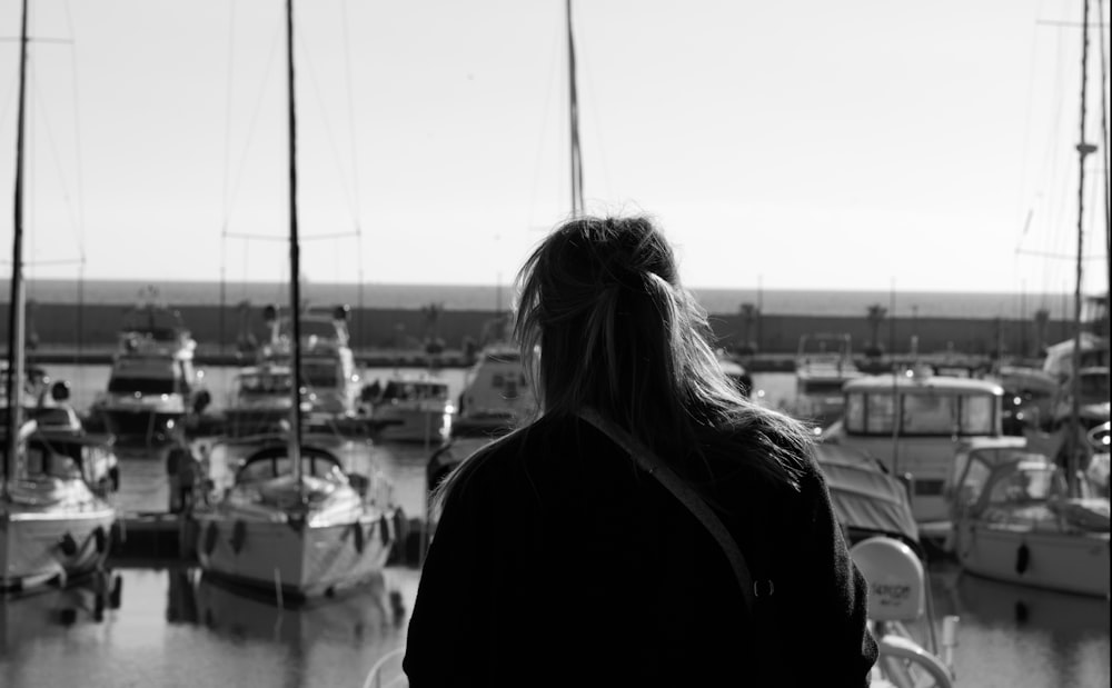 a woman standing in front of a harbor filled with boats