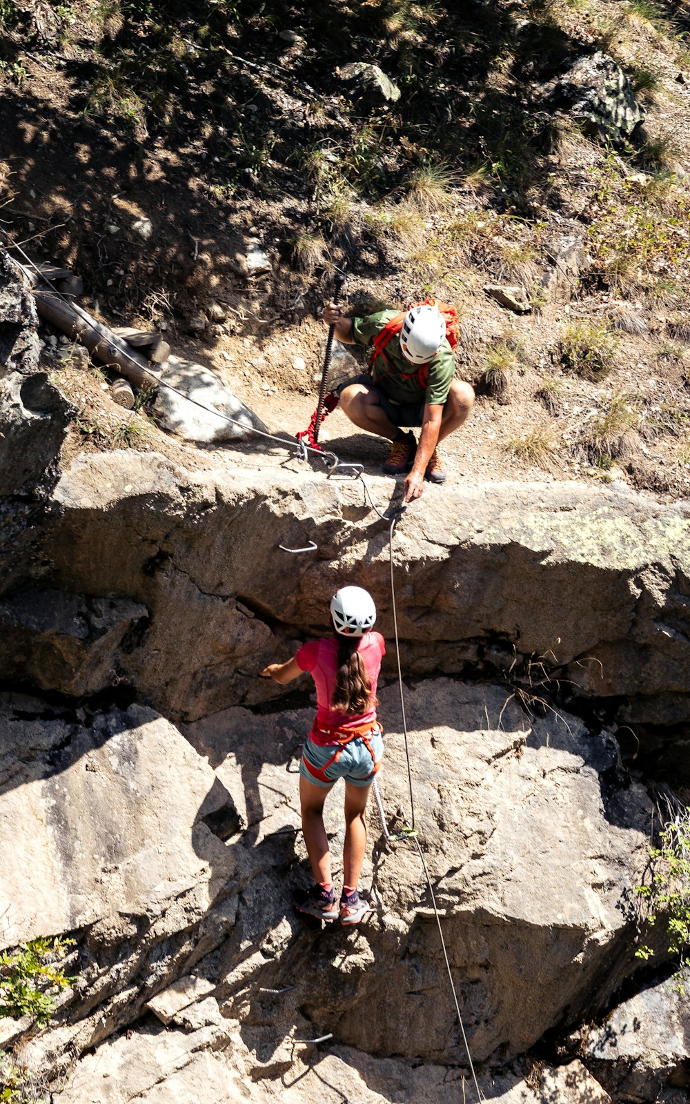 a couple of people climbing up the side of a mountain