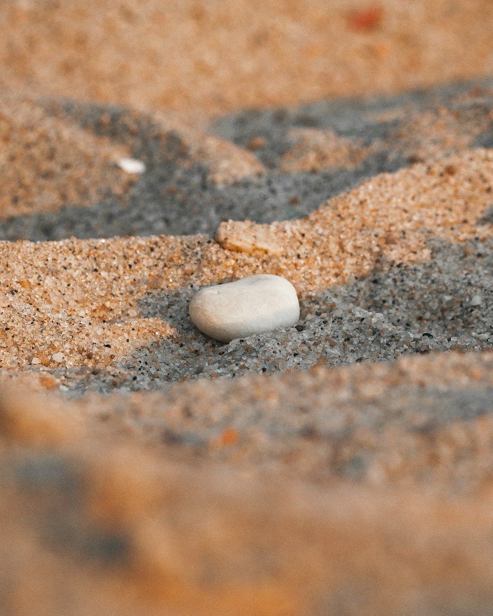 a white rock sitting on top of a sandy beach