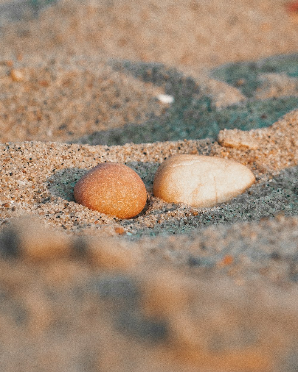 two rocks in the sand on a beach