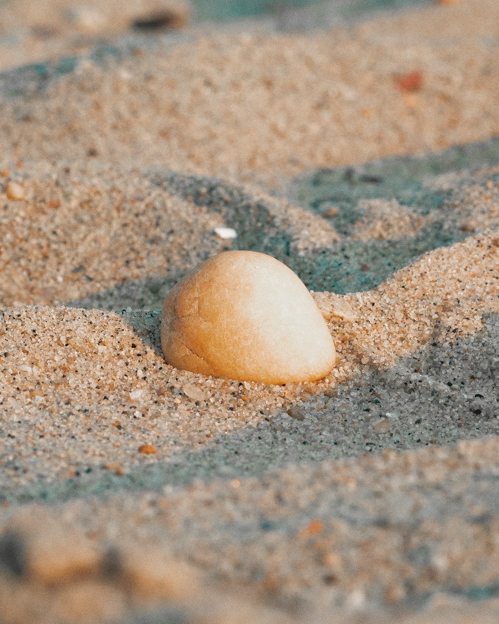 a rock sitting on top of a sandy beach