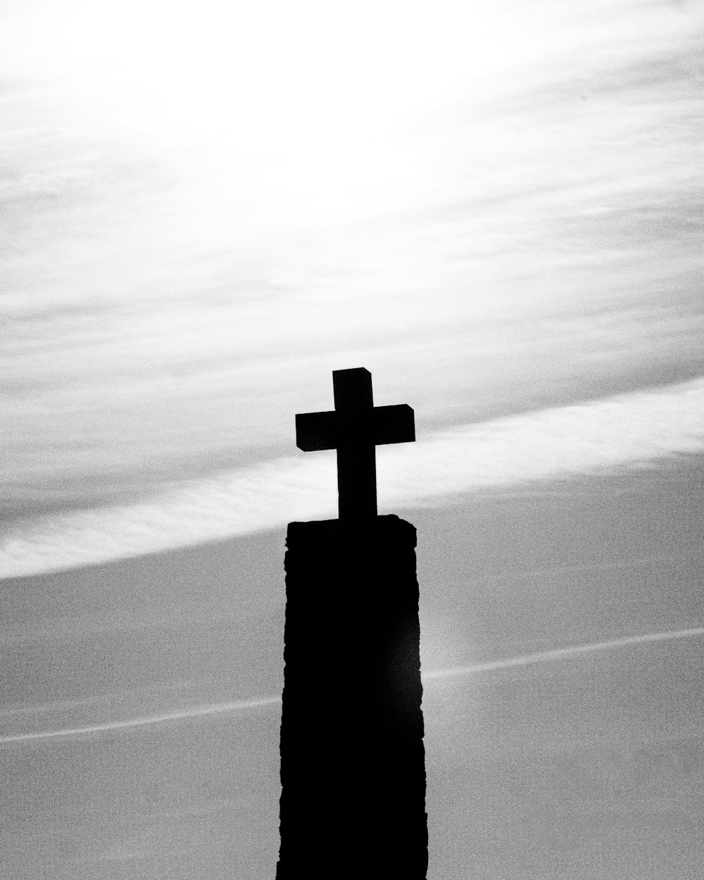 a black and white photo of a cross on a hill