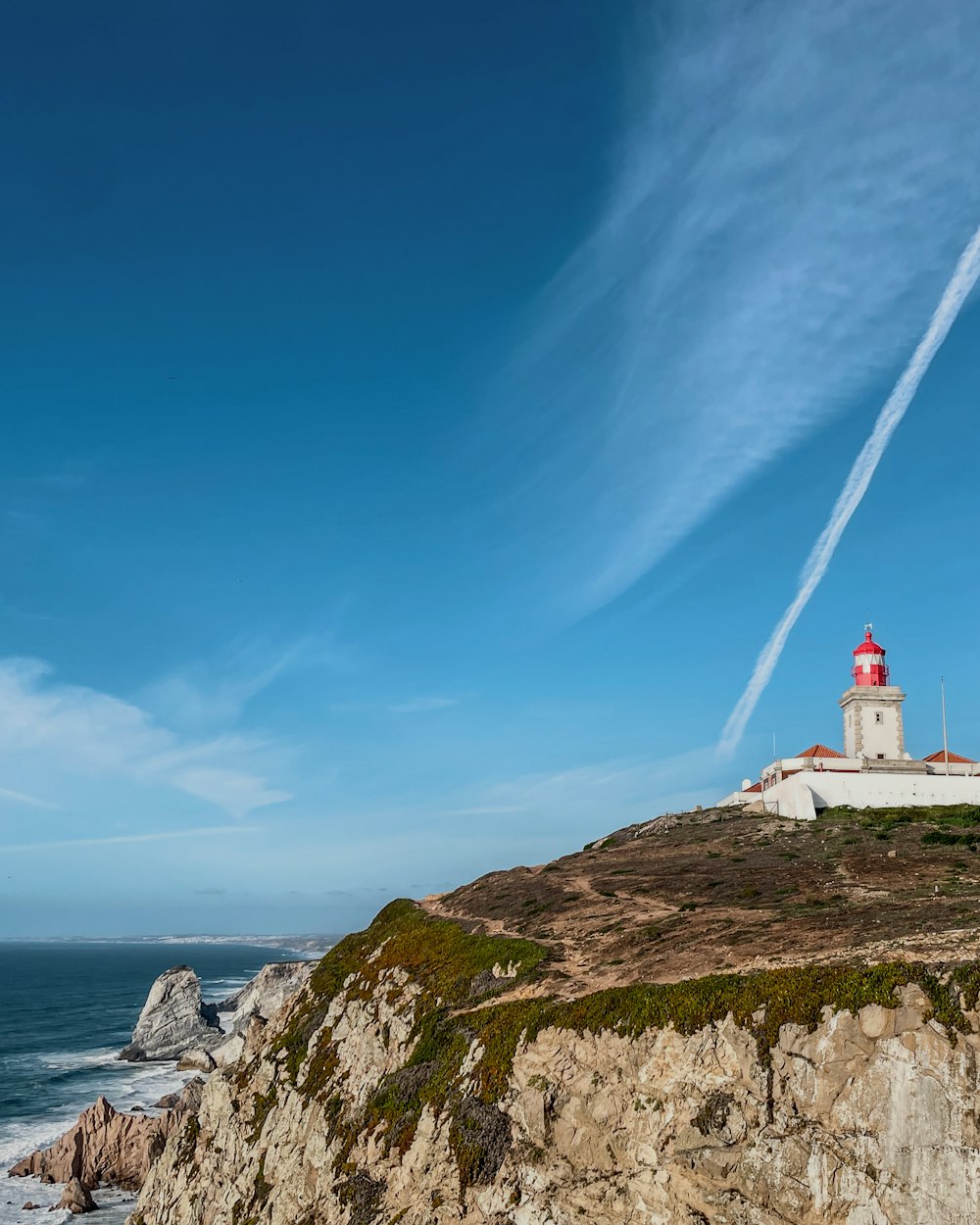 a lighthouse on top of a cliff near the ocean