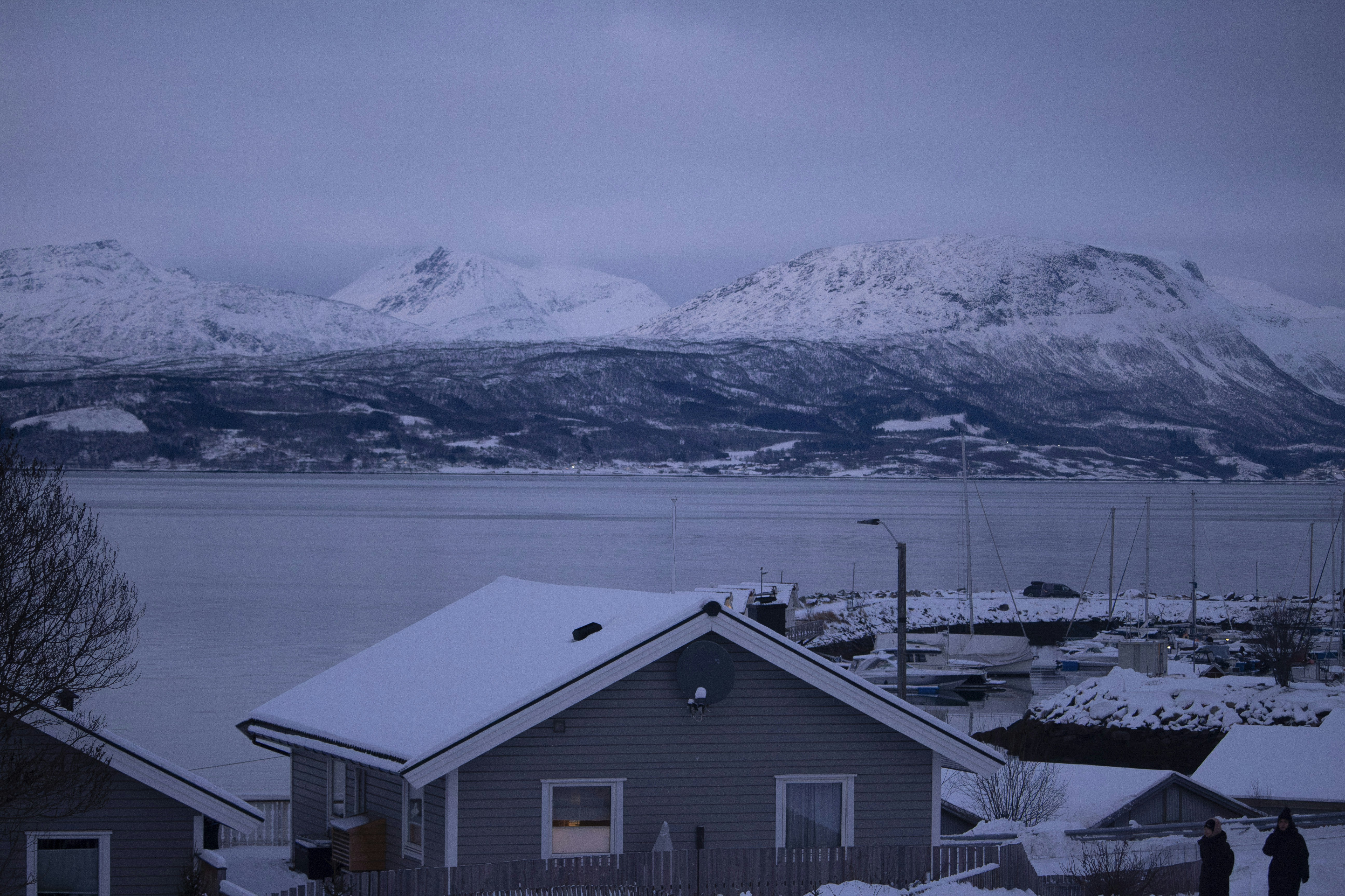 a couple of people standing outside of a house in the snow
