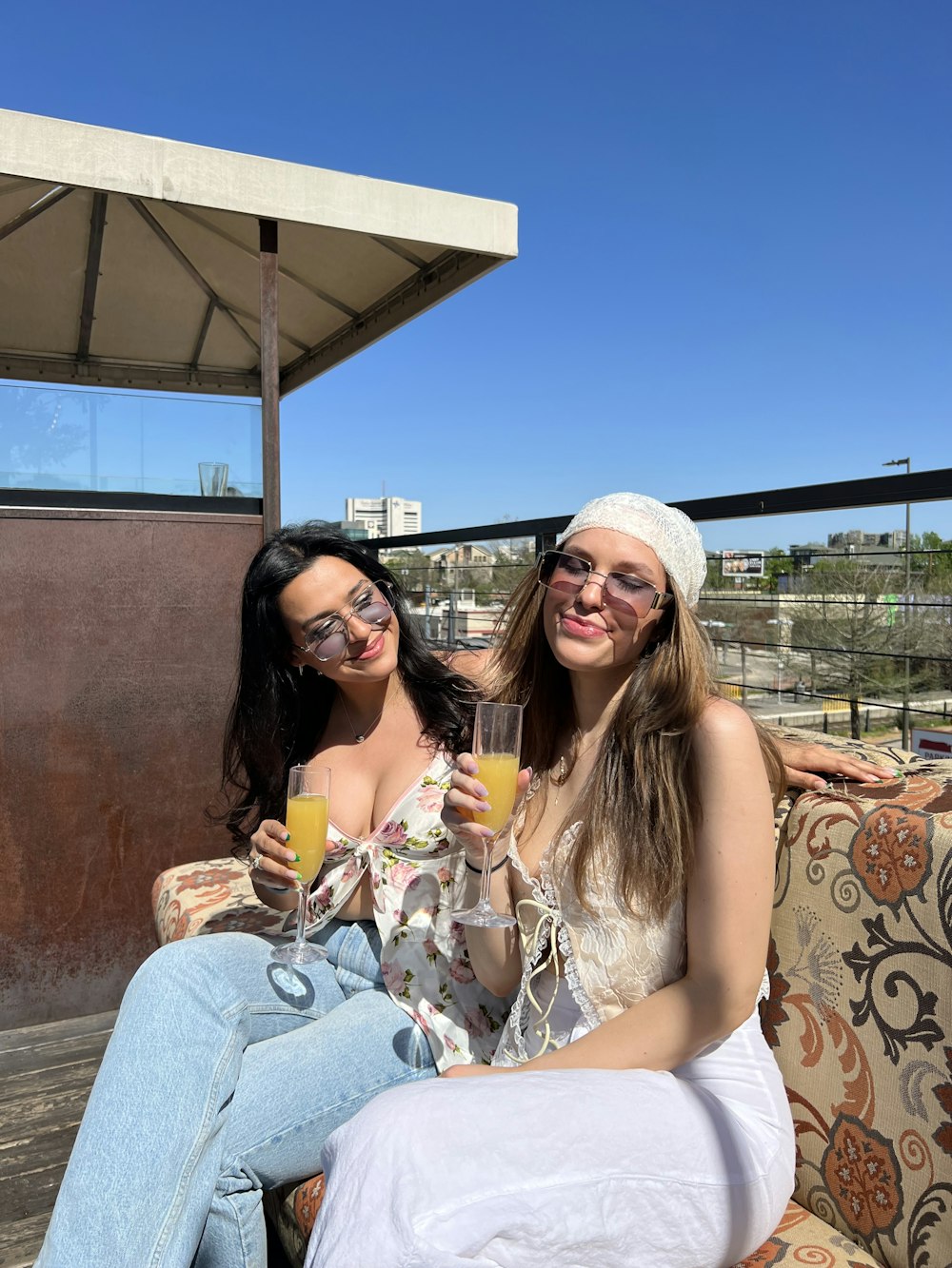 two women sitting on a couch holding drinks