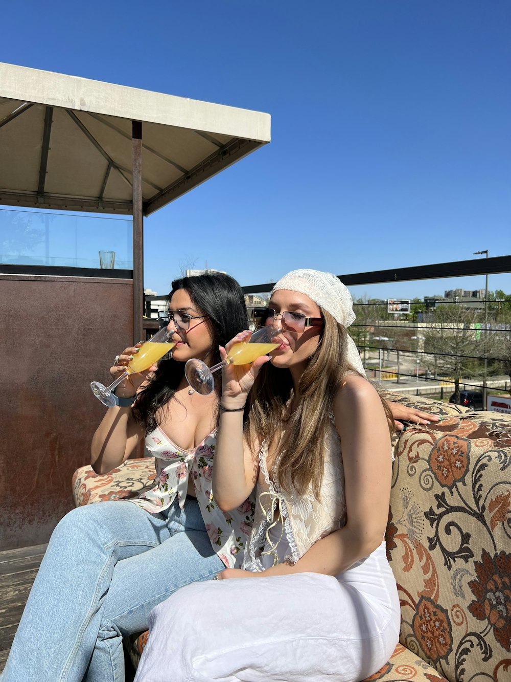 two women sitting on a couch drinking wine