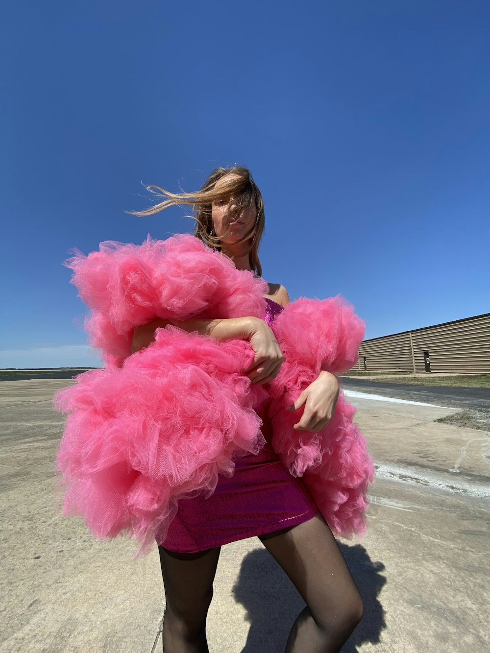 a woman in a pink dress is holding a pink coat