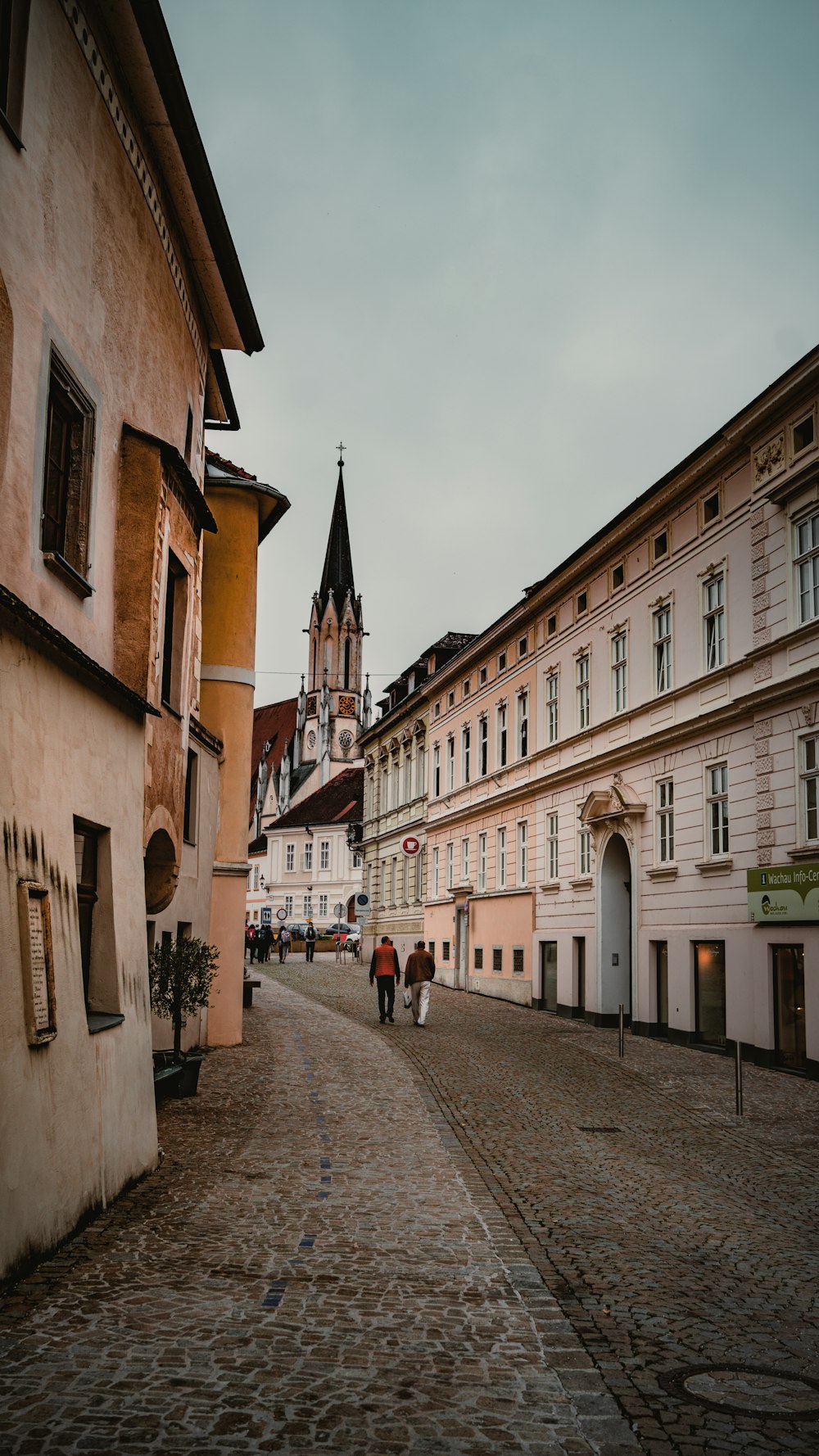 a couple of people walking down a cobblestone street