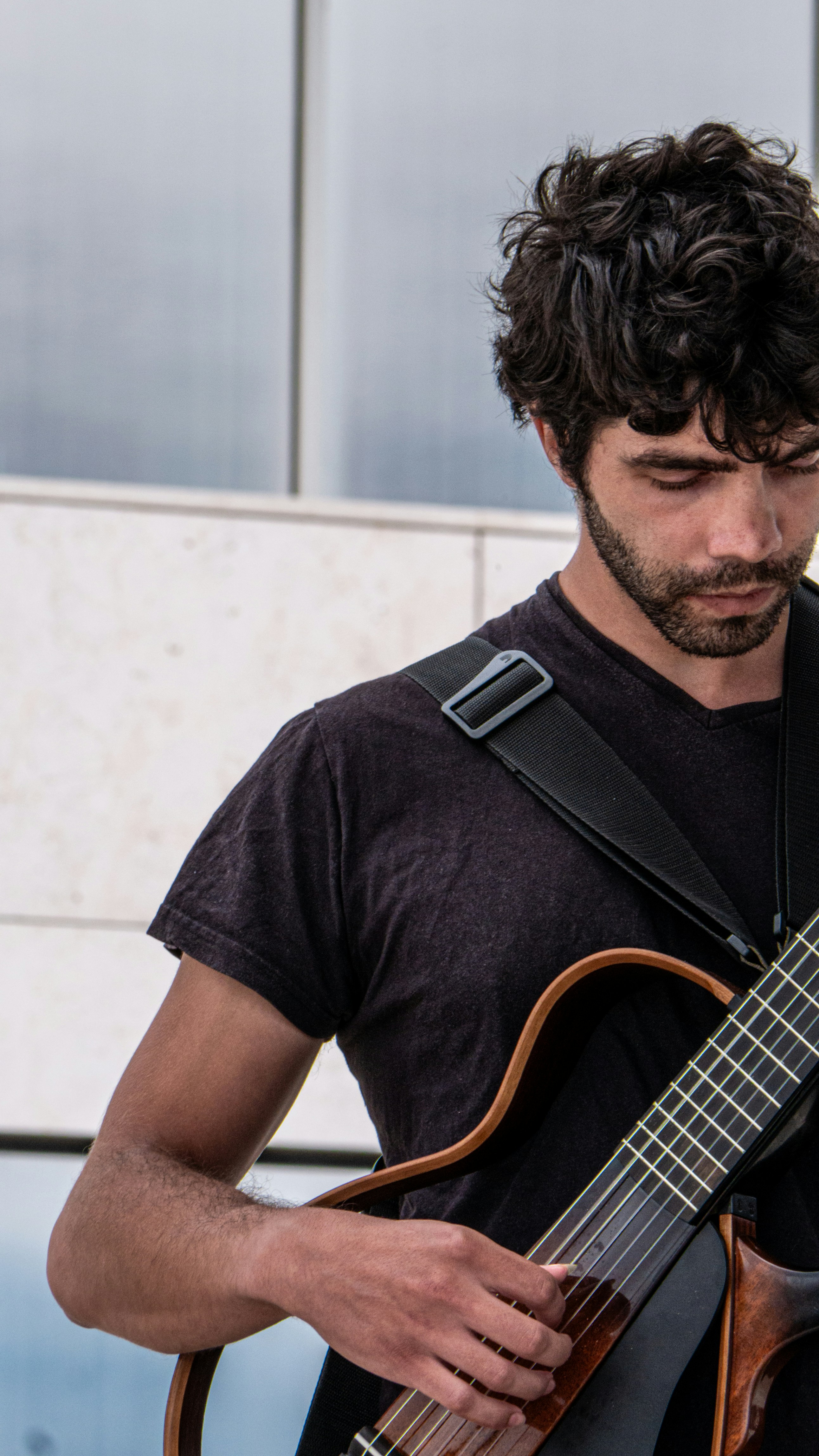 a man playing a guitar in front of a building