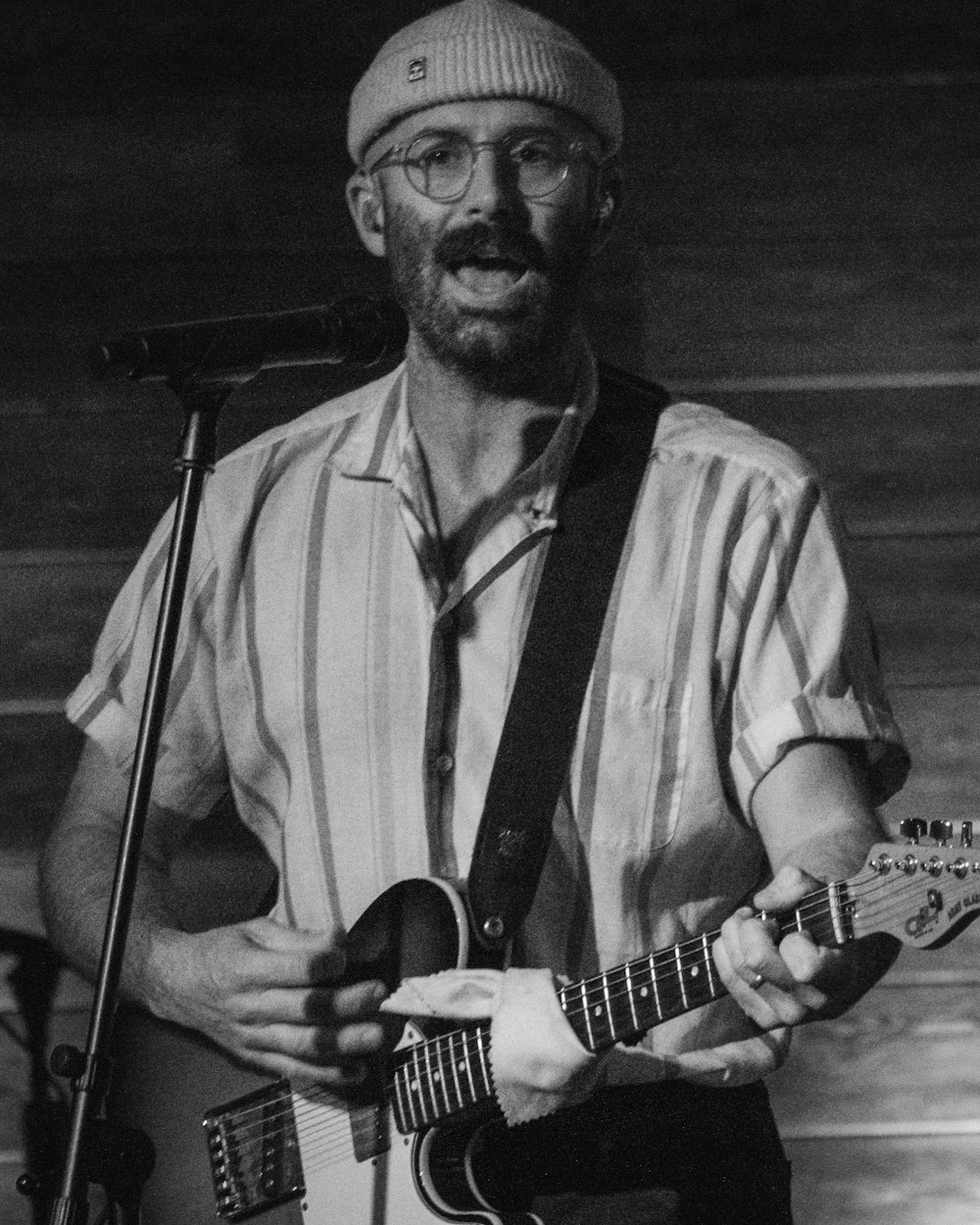 a man holding a guitar while standing in front of a microphone