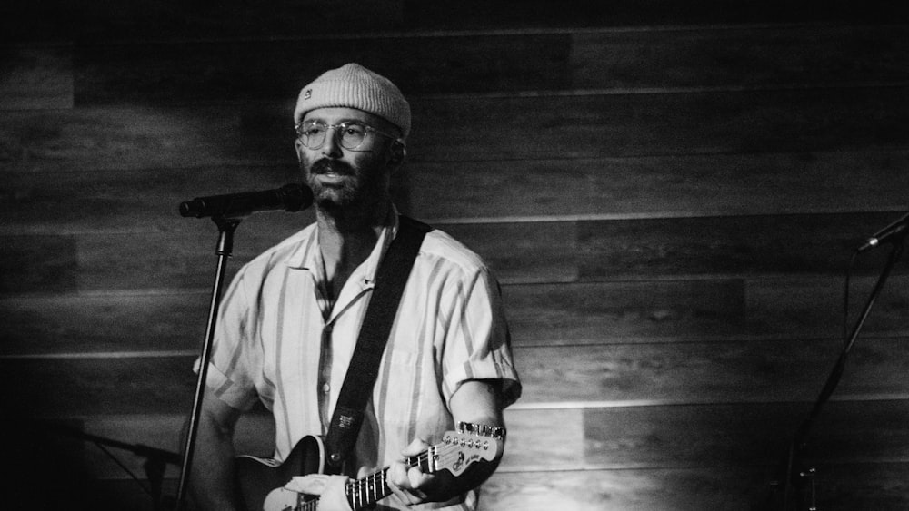 a man playing a guitar in front of a microphone