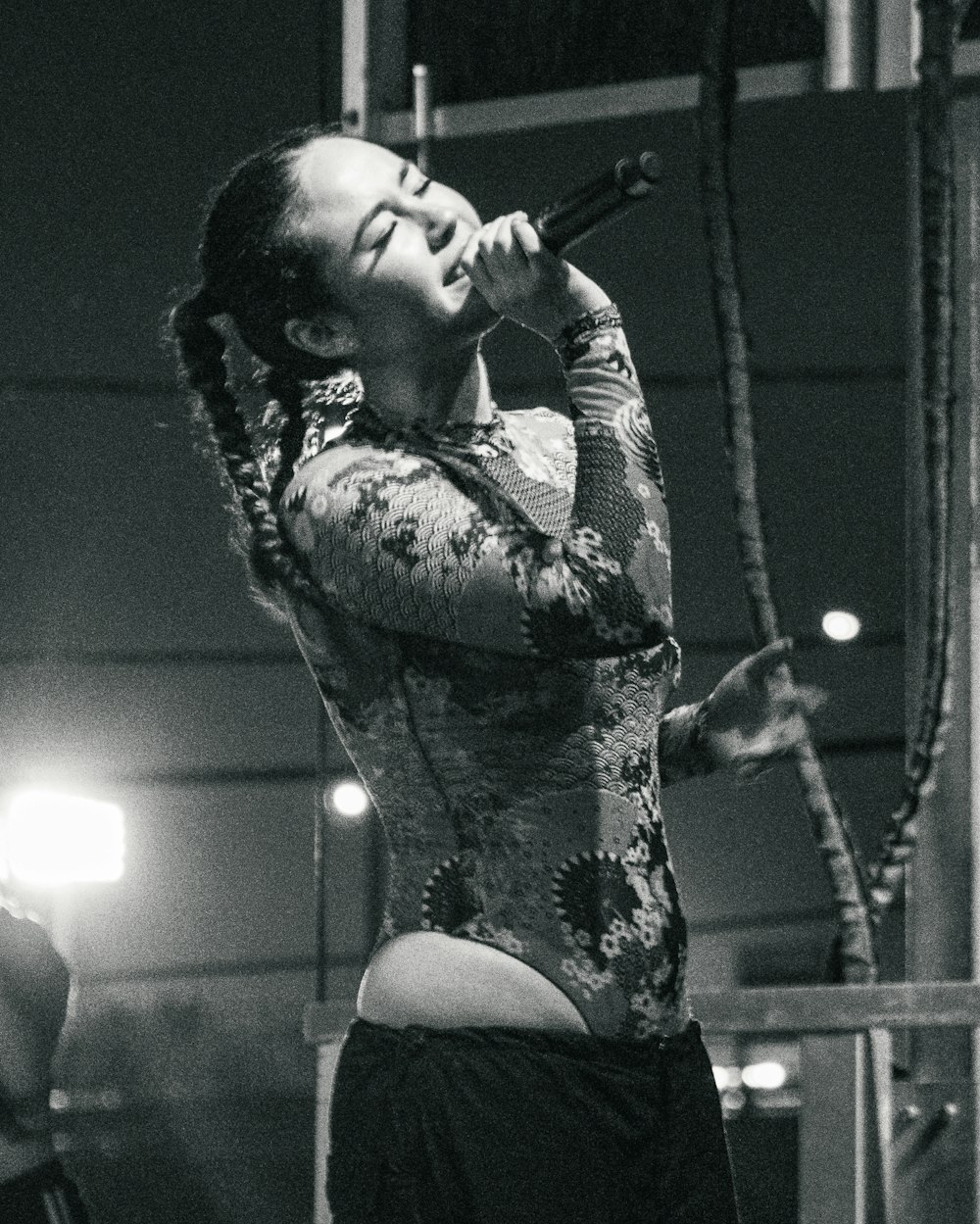 uma mulher cantando em um microfone em uma foto em preto e branco
