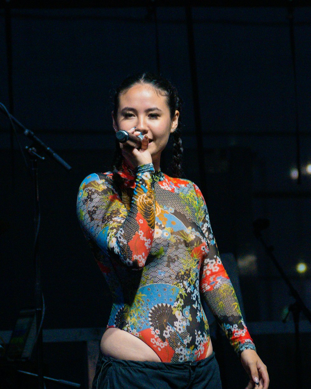 uma mulher em uma camisa colorida cantando em um microfone