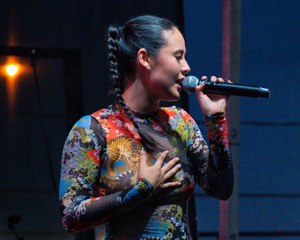 uma mulher em um vestido colorido cantando em um microfone