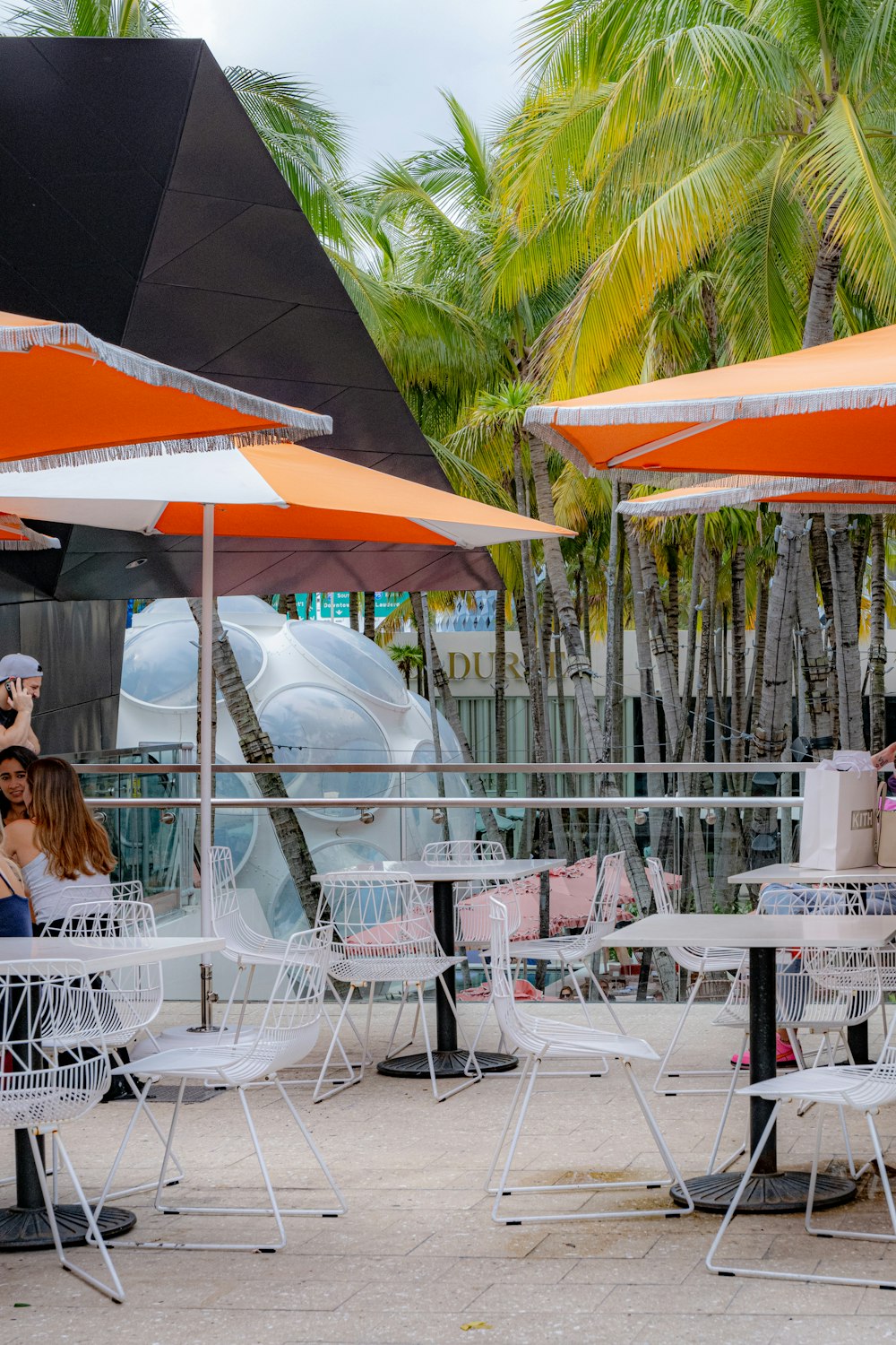 a group of people sitting at tables under umbrellas