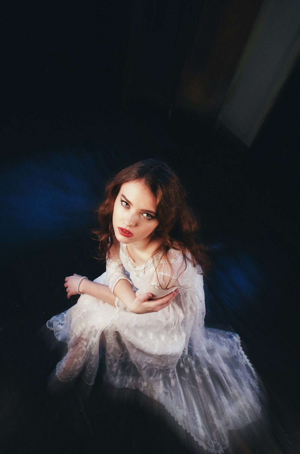 a young girl in a white dress sitting on the floor