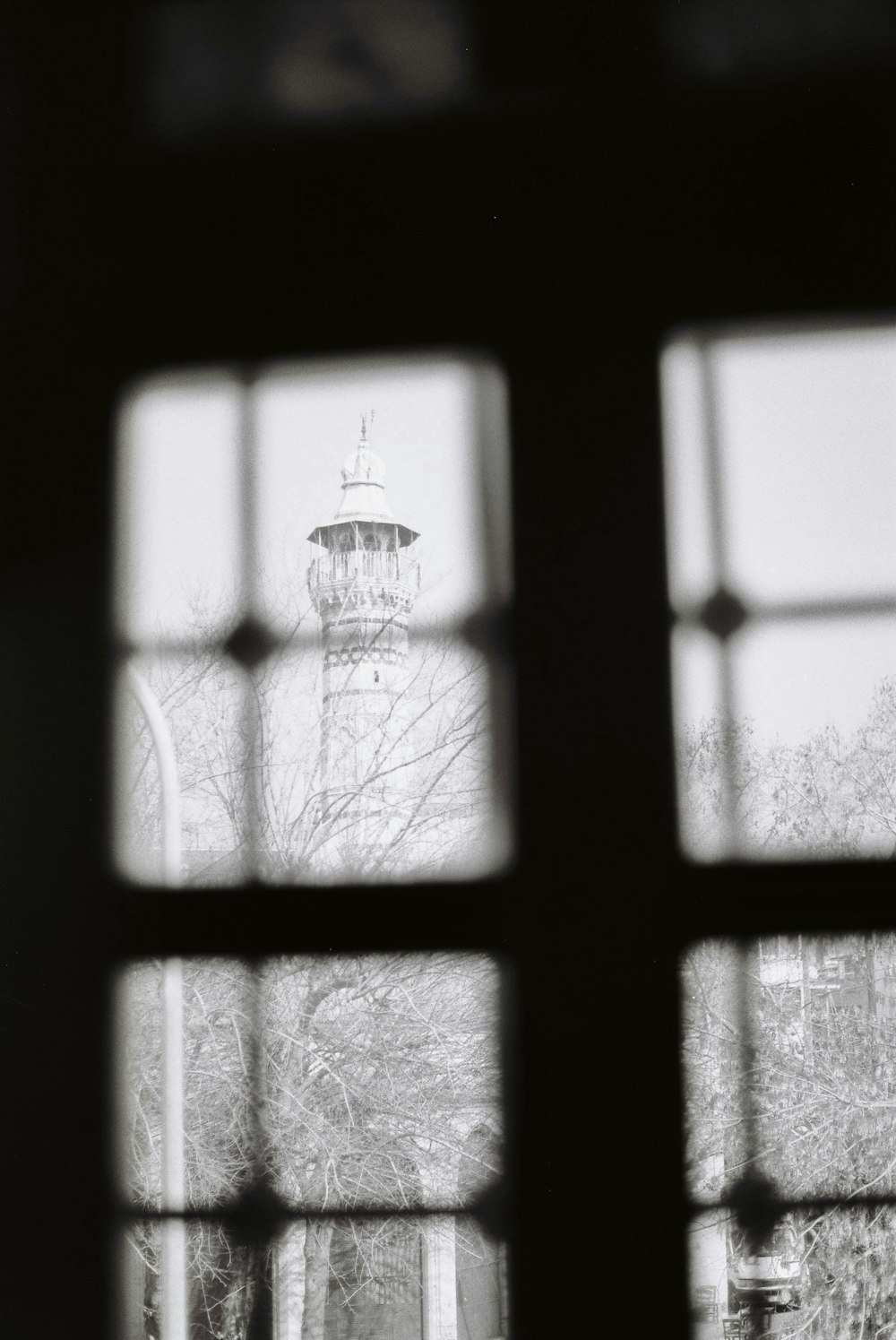 a black and white photo of a lighthouse through a window