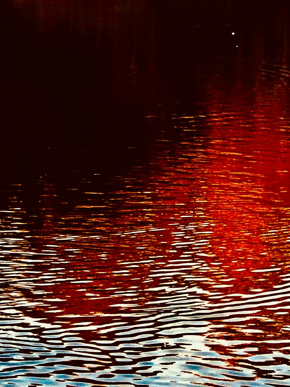 a large body of water with a red sky in the background