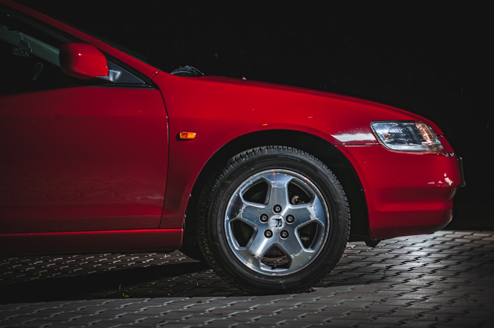a close up of a red car parked in the dark
