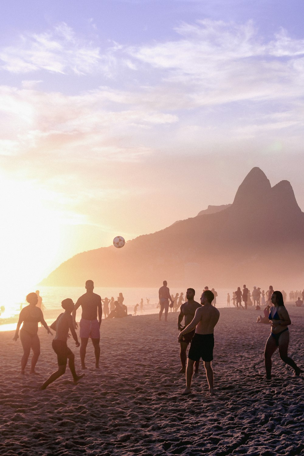 a group of people playing soccer on a beach