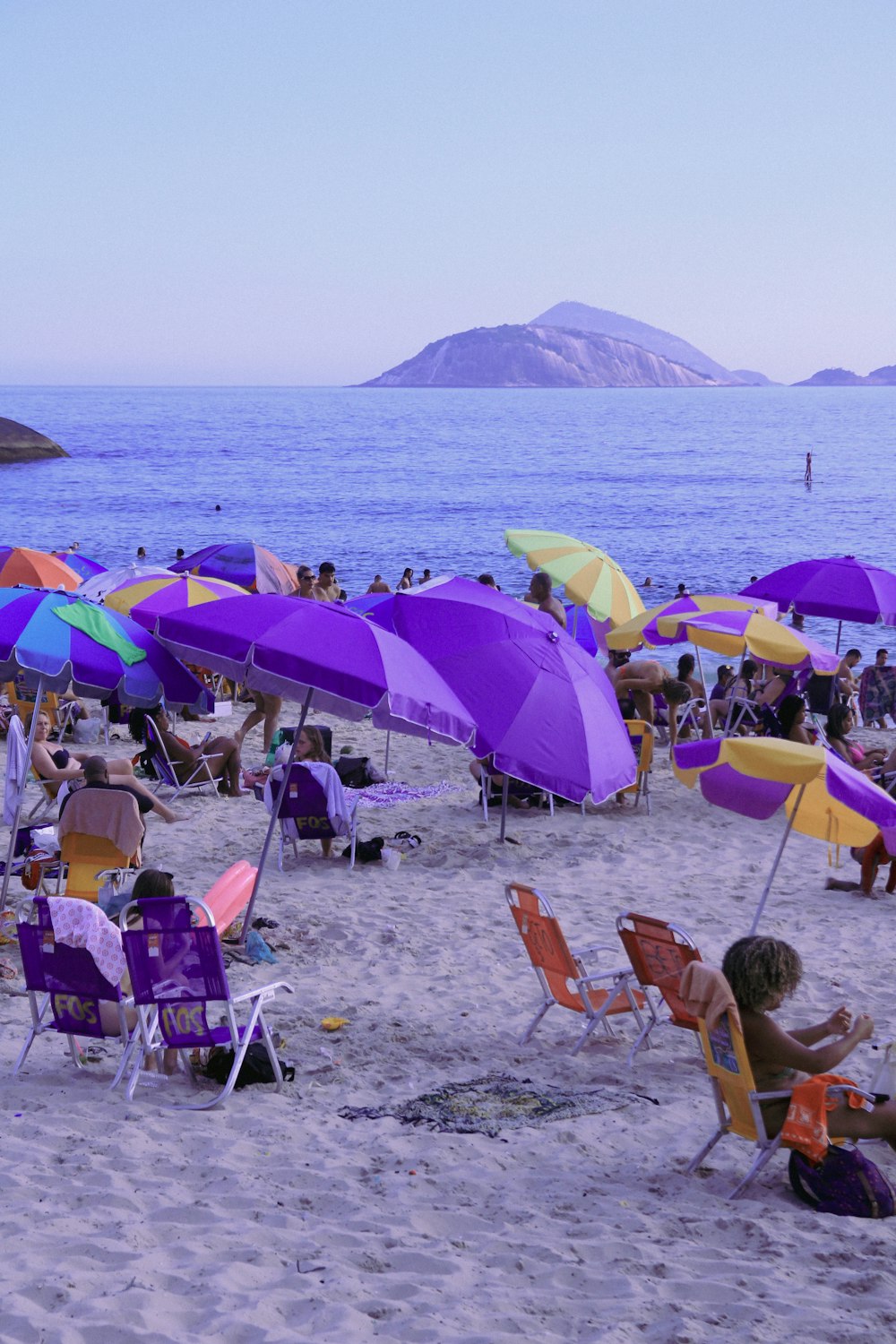 a group of people sitting on top of a sandy beach