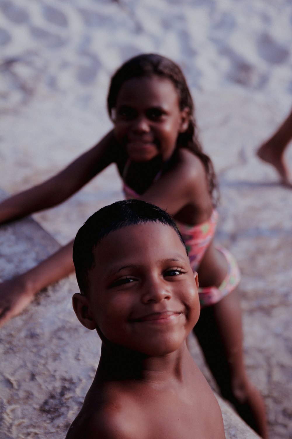 a couple of kids sitting on top of a sandy beach