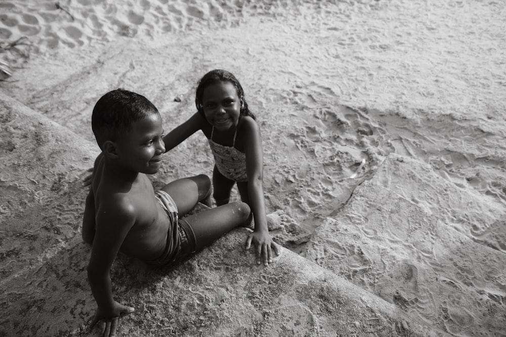 a couple of kids sitting on top of a sandy beach