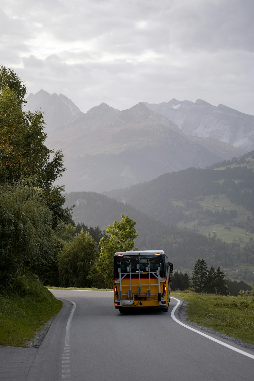 a bus driving down a road with mountains in the background