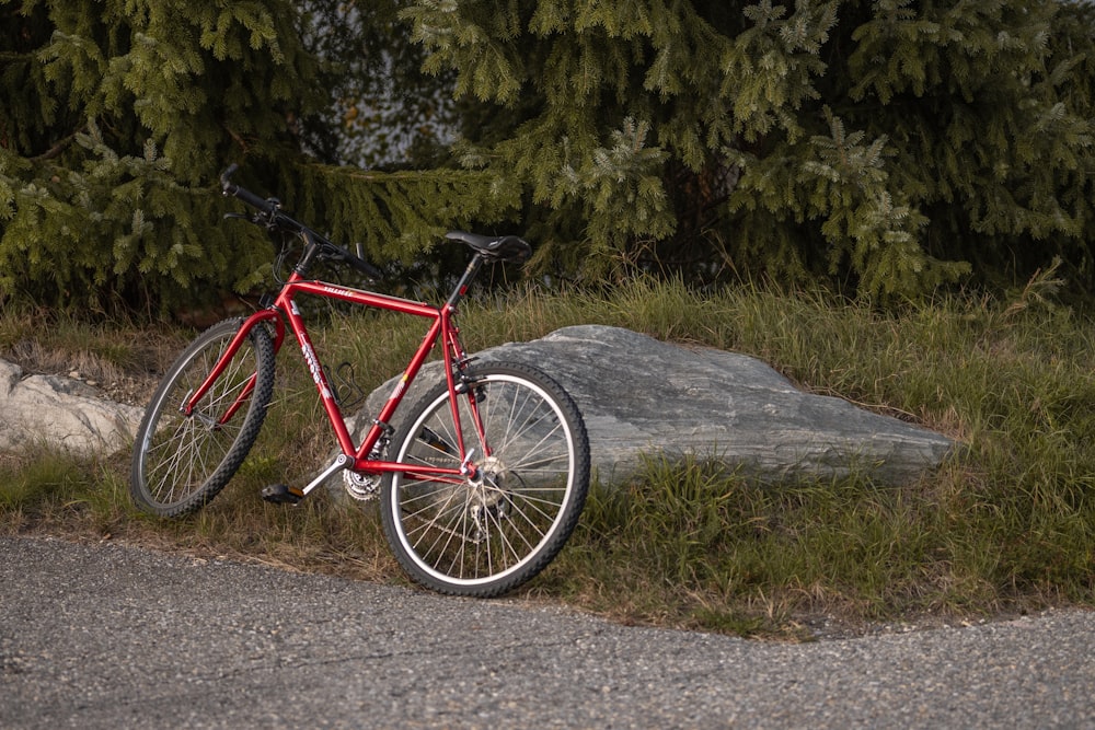 a red bike parked next to a large rock
