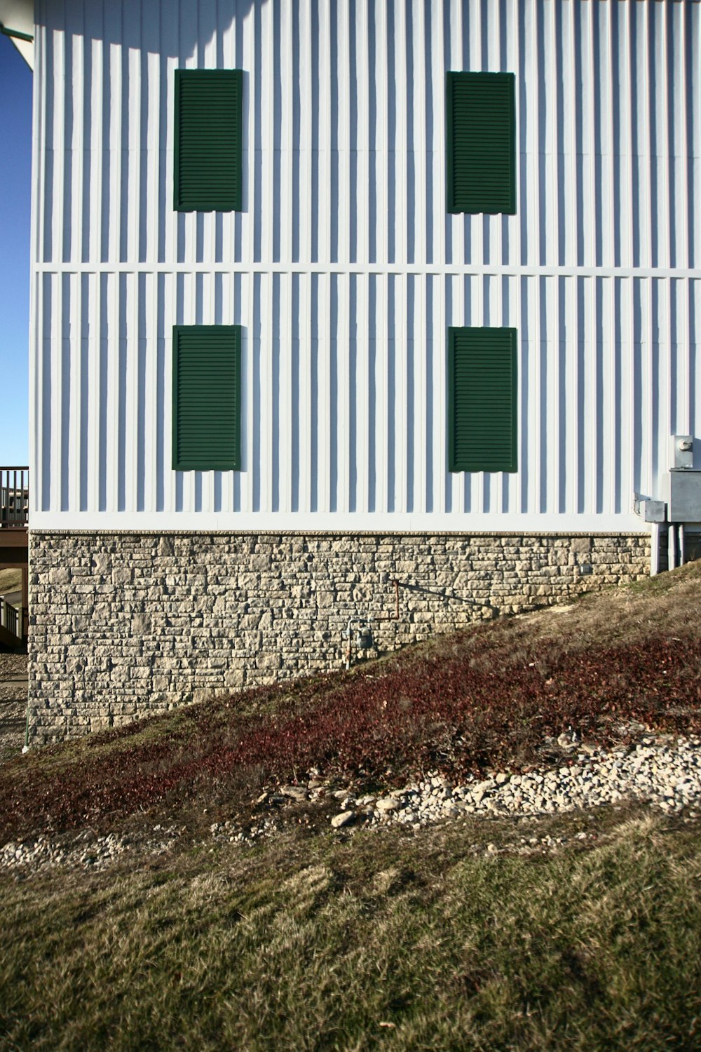 a white building with green shutters and a red fire hydrant