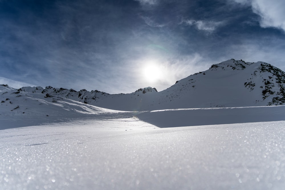 the sun is shining over a snowy mountain