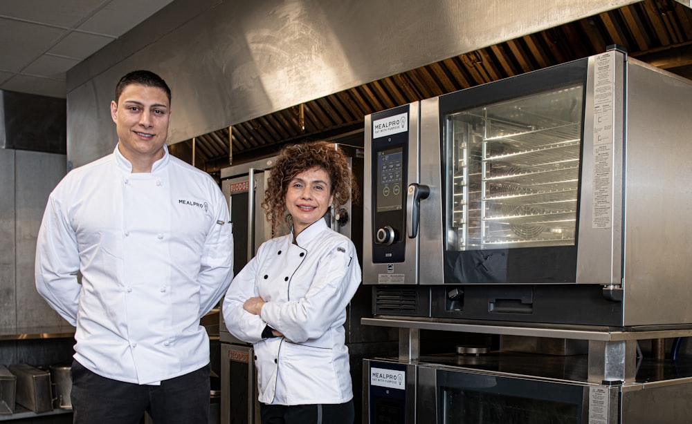 a man and a woman standing in front of an oven