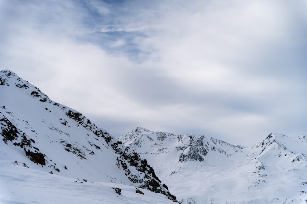 a mountain covered in snow under a cloudy sky