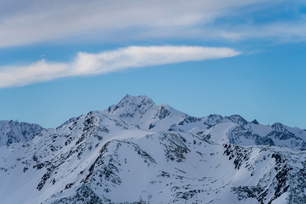 a mountain range covered in snow under a blue sky