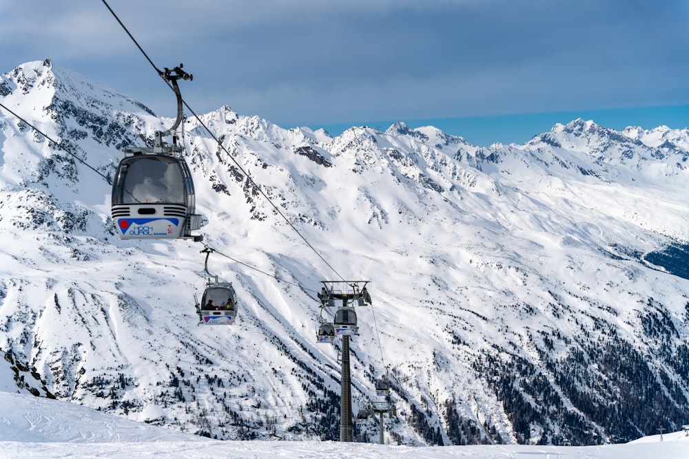 um teleférico subindo o lado de uma montanha coberta de neve