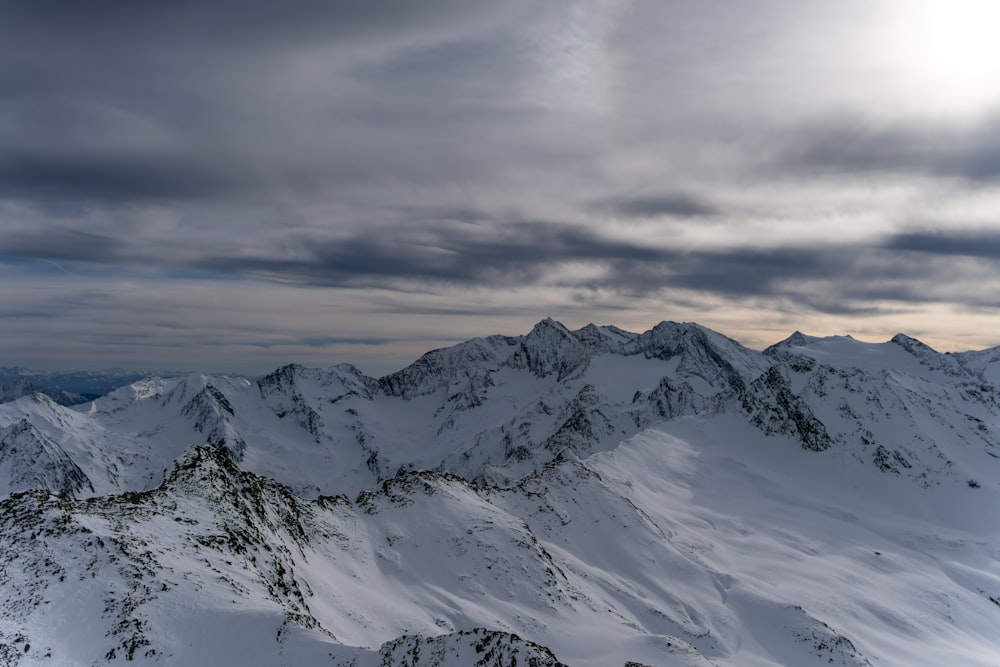 a snowy mountain range under a cloudy sky