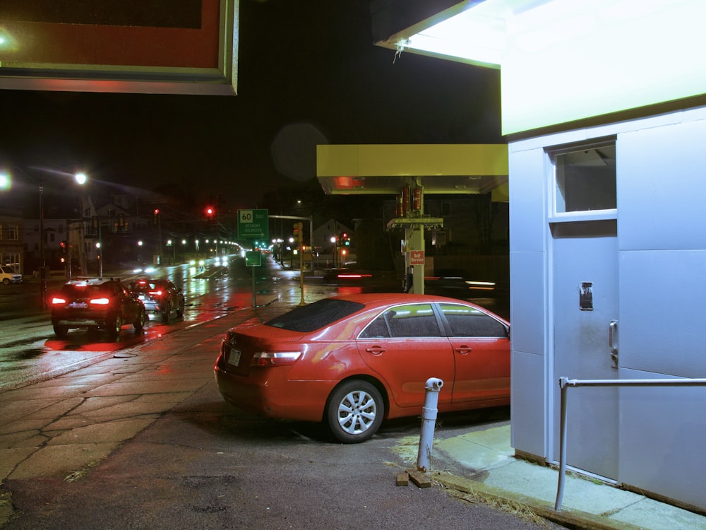 a red car parked in front of a gas station