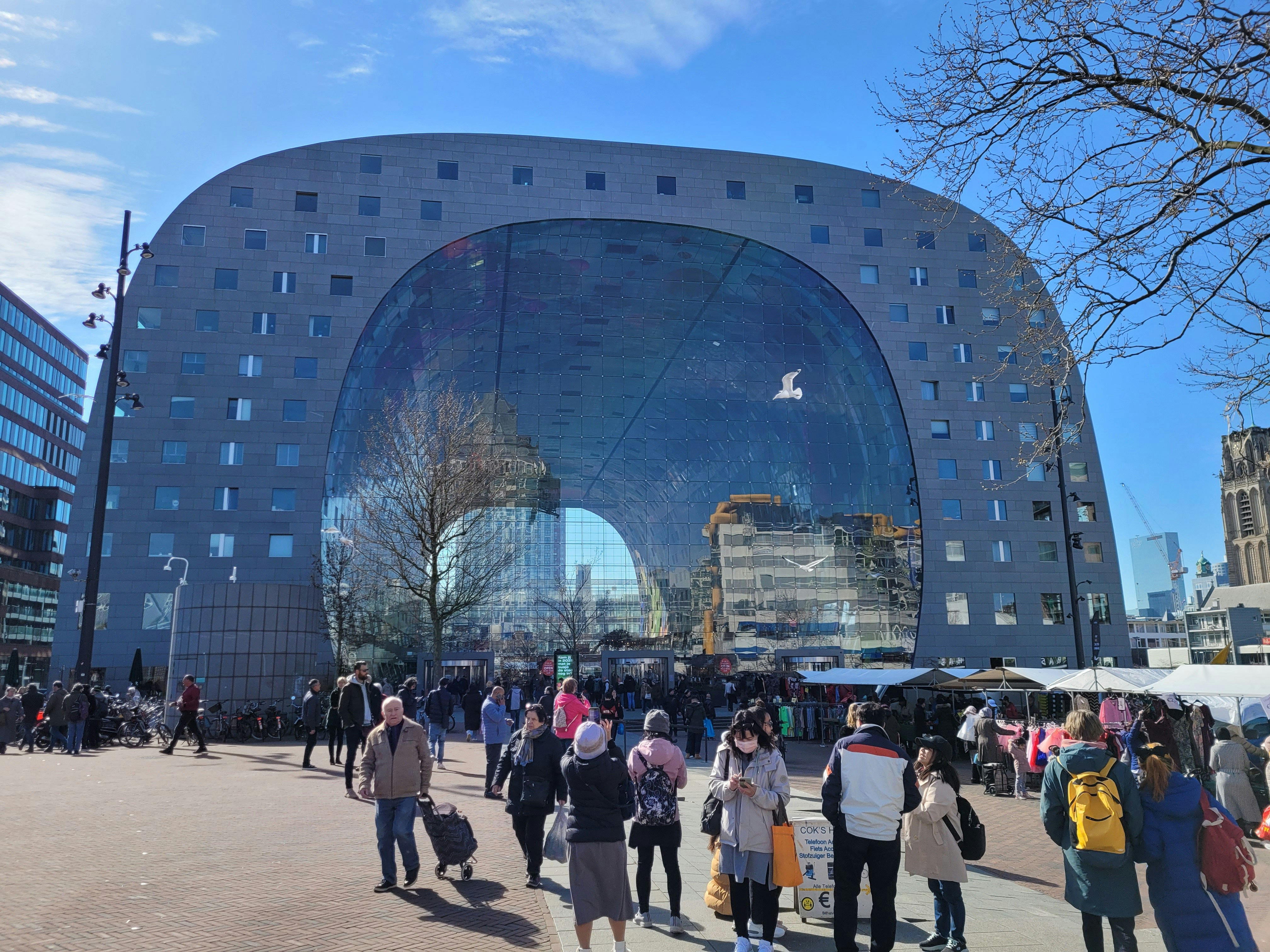 Feestvierders in oranje kleding tijdens Koningsdag in Rotterdam met skyline op de achtergrond