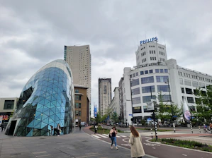 a couple of people walking down a street next to tall buildings