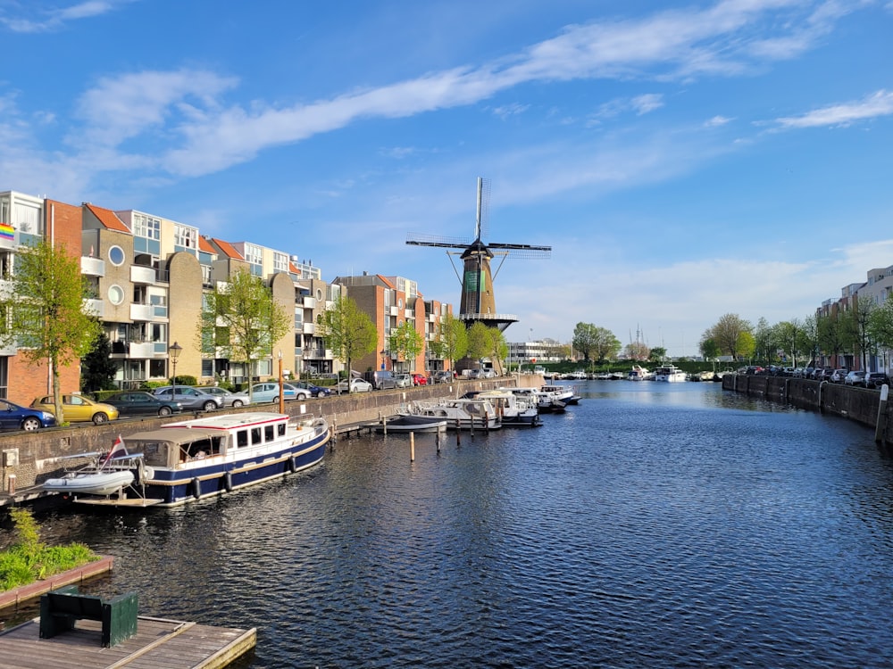 a river with boats and a windmill in the background