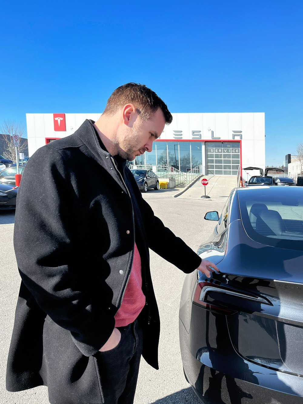 a man standing next to a car in a parking lot