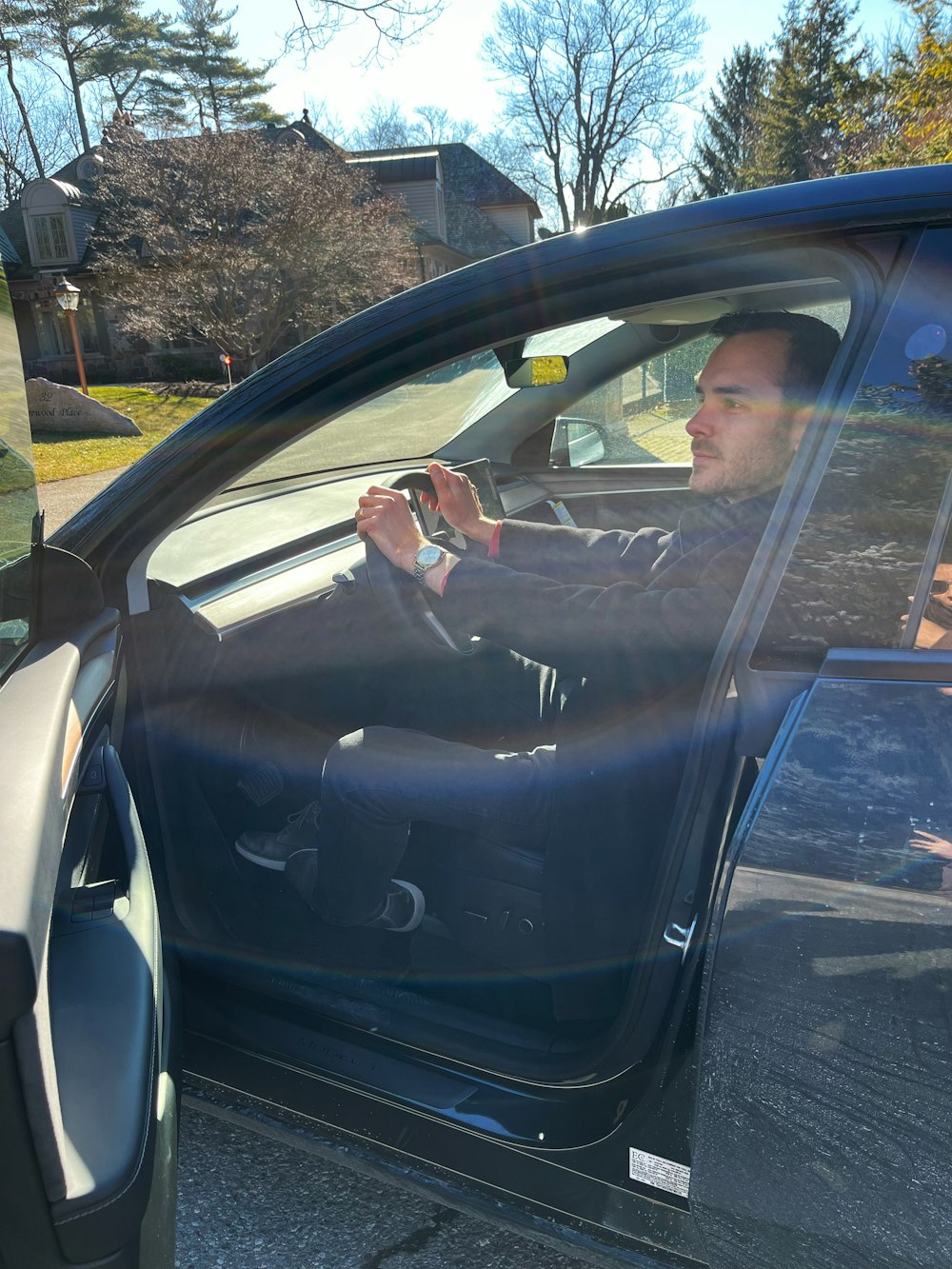 a man sitting in a car holding a steering wheel