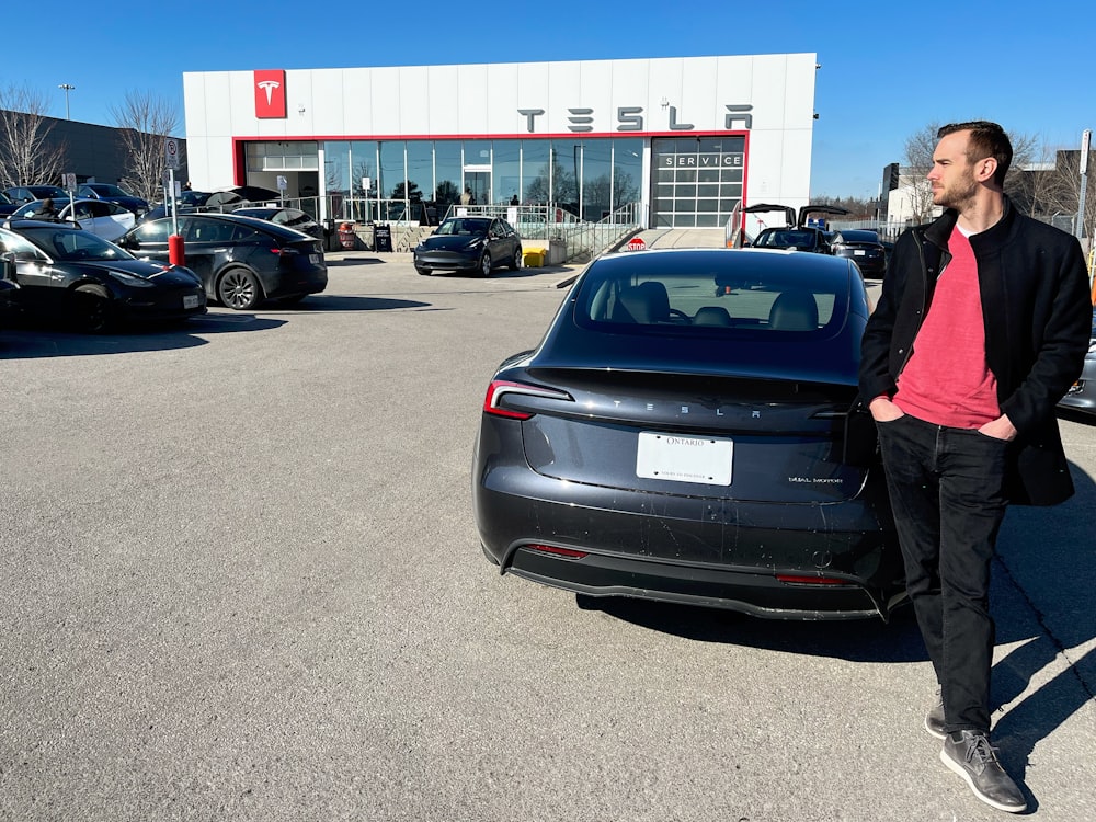 a man standing next to a car in a parking lot