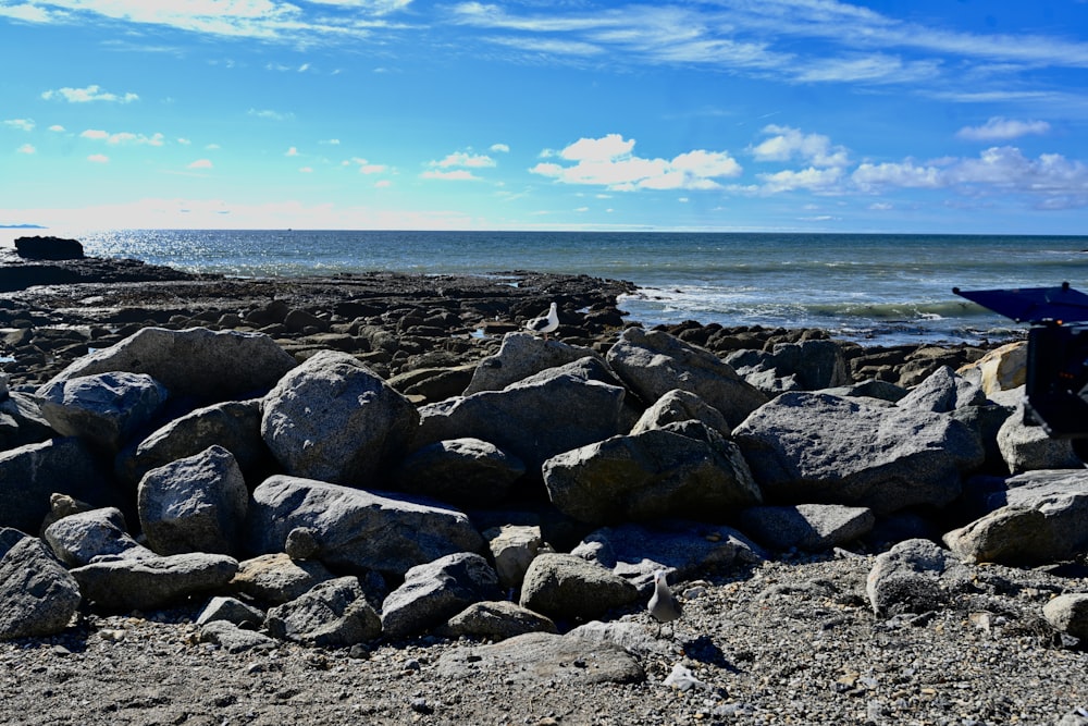 a blue umbrella sitting on top of a pile of rocks