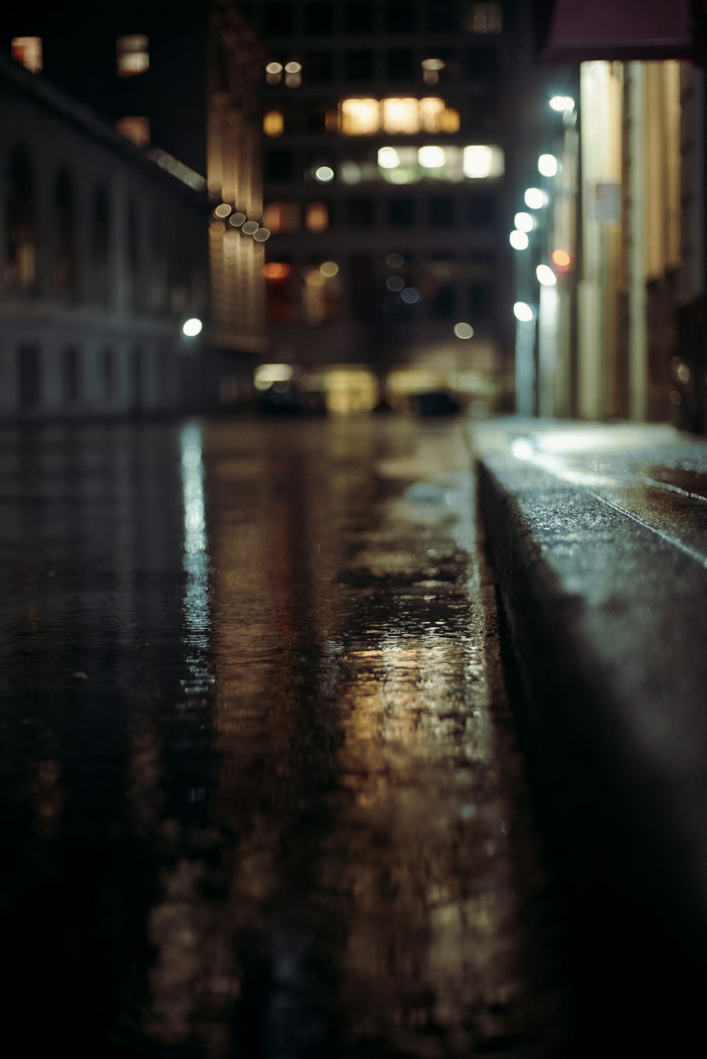 a wet sidewalk in the middle of a city at night