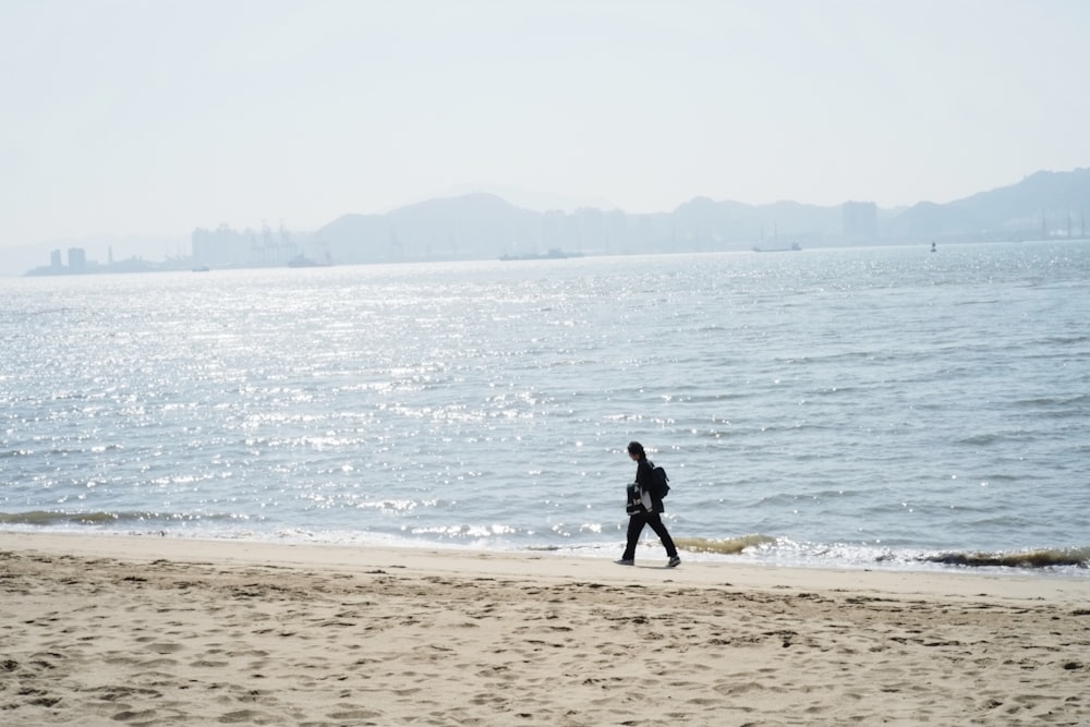 a person walking on a beach next to the ocean