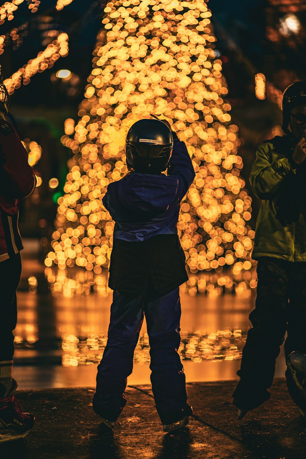 a little boy standing in front of a christmas tree