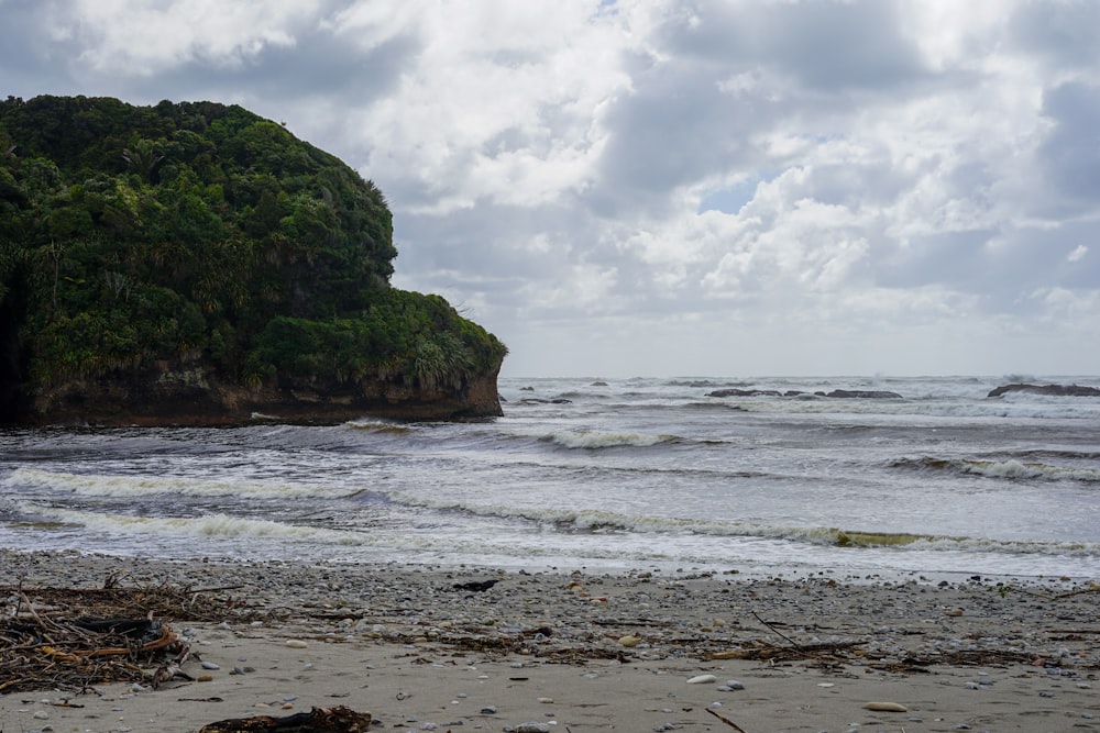 a beach with a rock outcropping in the middle of the ocean