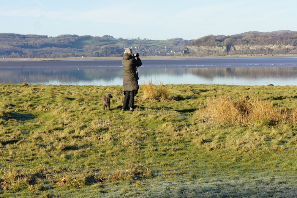 a person taking a picture of a lake with a dog