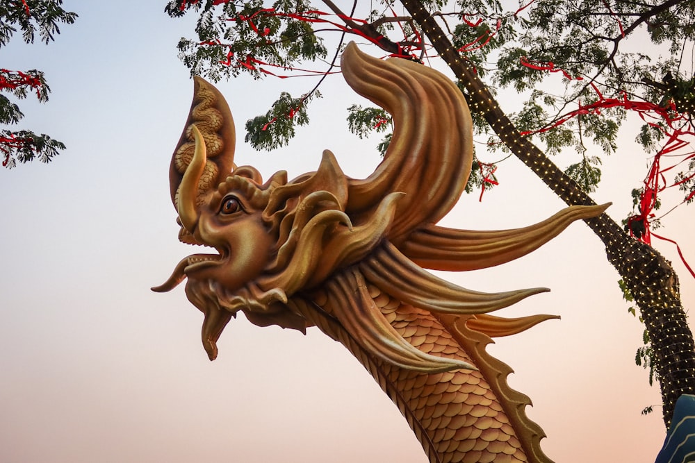 a golden dragon statue sitting next to a tree